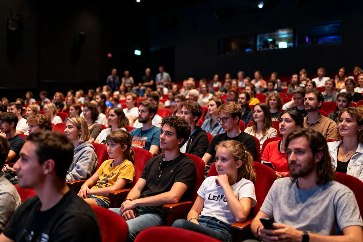 Audience captivée par la présentation de Lee Fou dans une salle de cinéma.